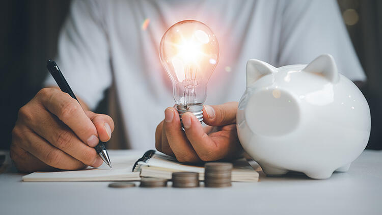 電球を持ちメモを取る男性とコインと貯金箱